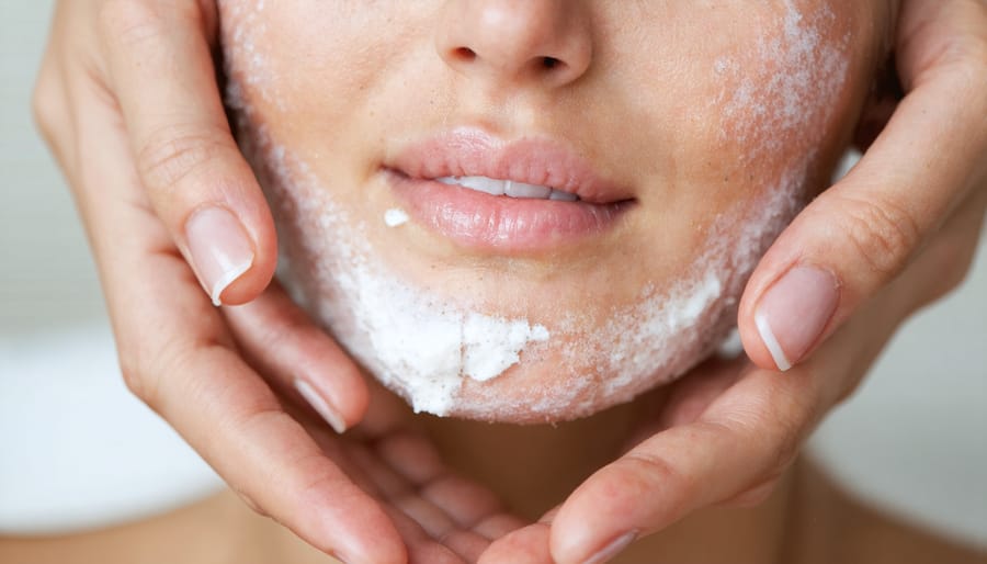 Hands applying a facial scrub to exfoliate the skin